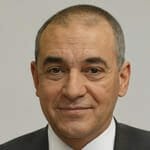 a man wearing a suit and tie smiling at the camera