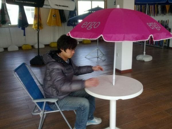 a boy sitting at a table with a umbrella