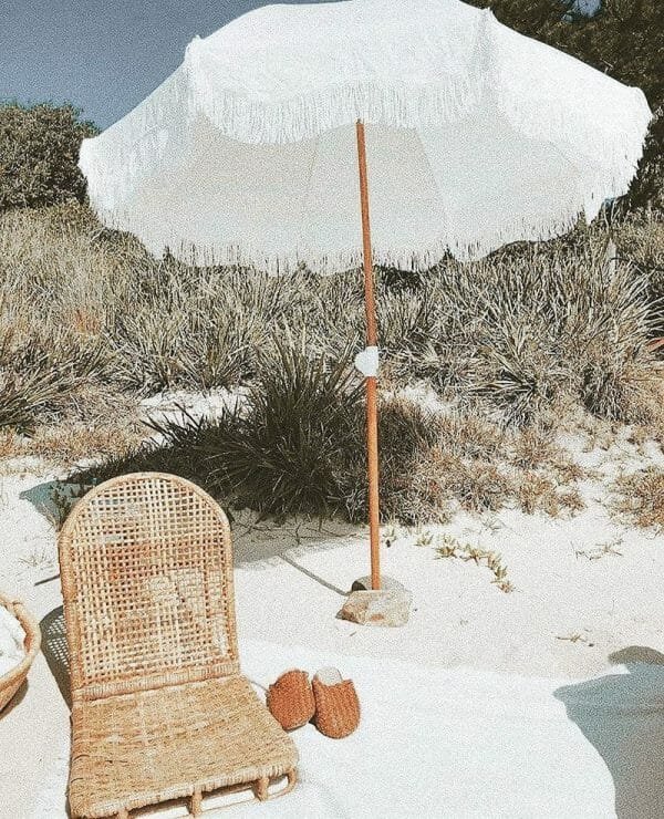 A wicker chair on the beach with a 5.5 Ft Fringe Cotton Beach Umbrella.