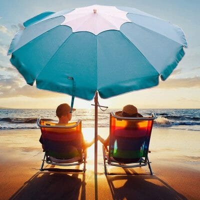 a couple of people sitting at a beach umbrella in the rain