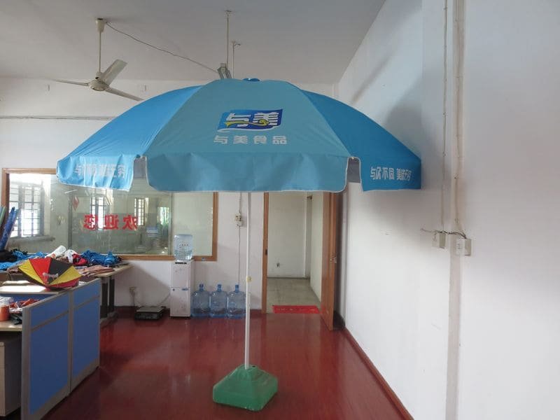 A 2.4M Oxford Beach Umbrella is sitting on a wooden floor in an office.