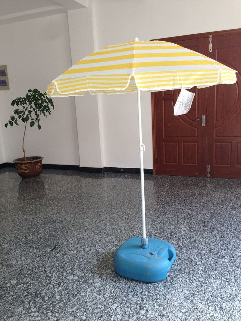 A 1.2M Polyester Beach Umbrella sitting on a concrete floor.