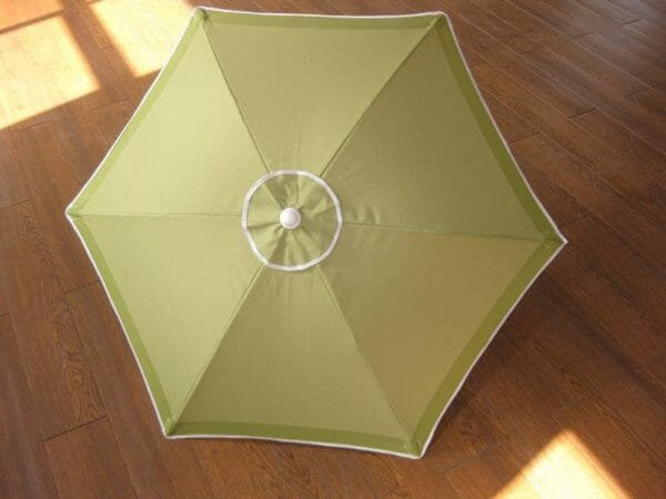 A 1.2M Polyester Beach Umbrella sitting on a wooden floor.