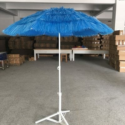 A 1.8m Thatched Beach Umbrella on a stand in a warehouse.