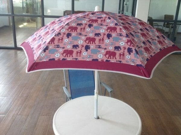 A 1.2M Polyester Beach Umbrella with elephants on it sits on top of a table.