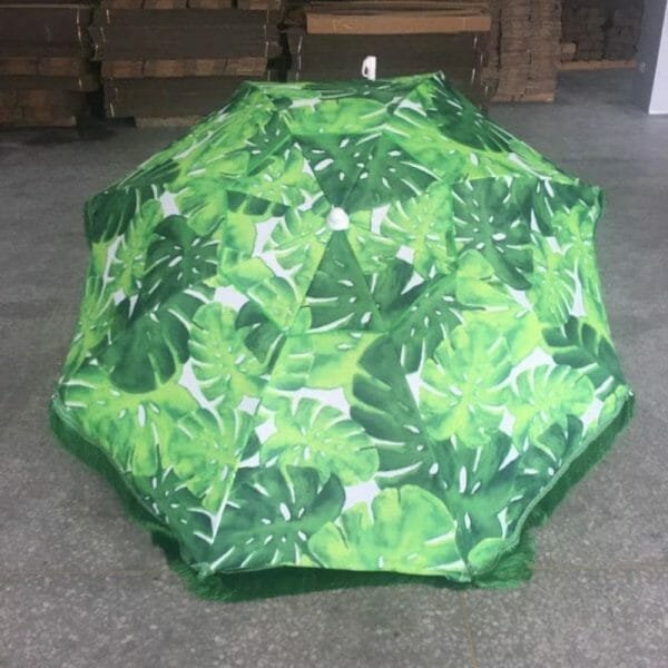 An 1.8M Fringe 400g Polyester Green Beach Umbrella | ARDECO with tropical leaves on it.