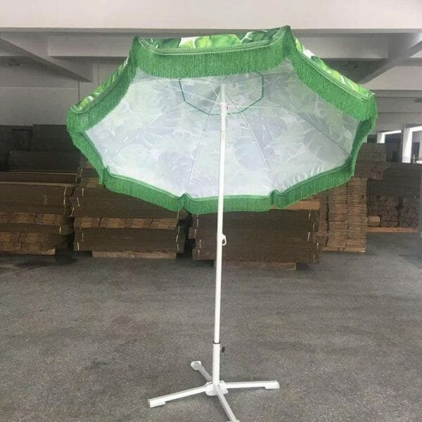 A 1.8M Fringe 400g Polyester Green Beach Umbrella | ARDECO on a stand in a warehouse.