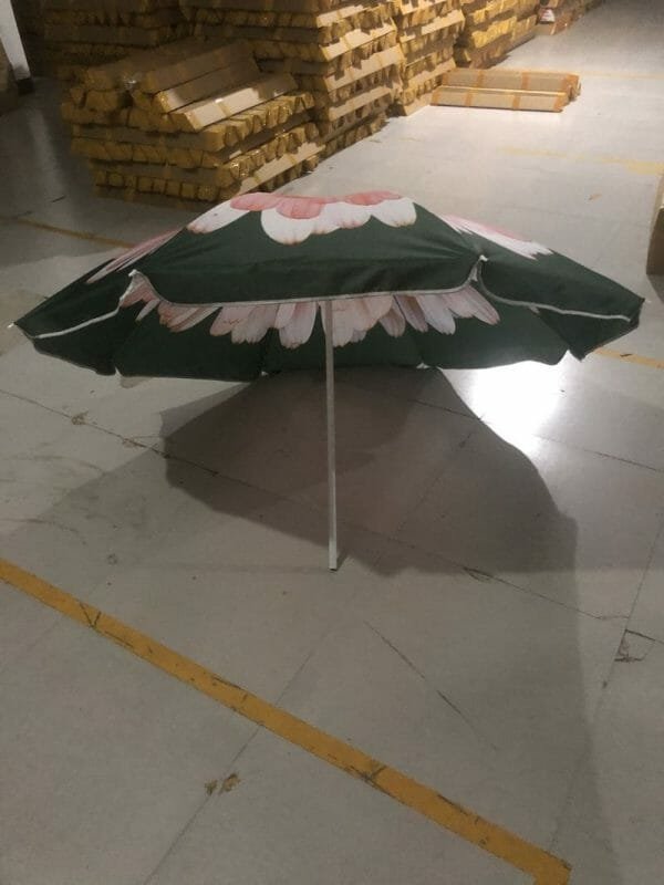 An 1.8M Polyester Black & Yellow Beach Umbrella with flowers on it sitting in a warehouse.