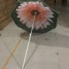 An 1.8M Polyester Black & Yellow Beach Umbrella with a flower on it sitting in a warehouse.
