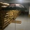 A 1.8M Polyester Black & Yellow Beach Umbrella in a warehouse filled with pallets.