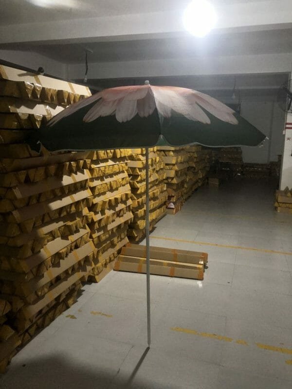 A 1.8M Polyester Black & Yellow Beach Umbrella in a warehouse filled with pallets.