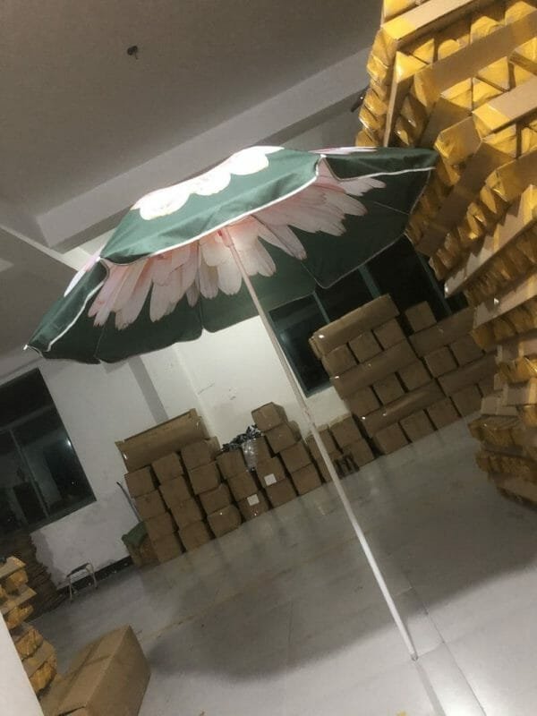 A 1.8M Polyester Black & Yellow Beach Umbrella sitting in a warehouse.