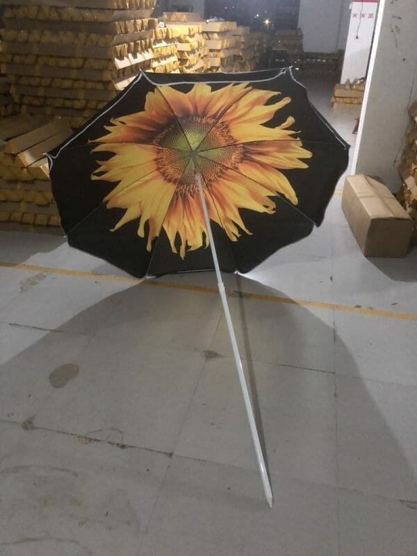 An 1.8M Polyester Black & Yellow Beach Umbrella with a sunflower on it in a warehouse.