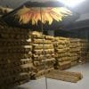 The 1.8M Polyester Black & Yellow Beach Umbrella with a sunflower on it is sitting in a warehouse.