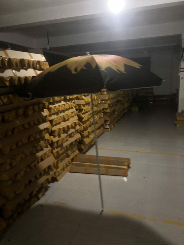 A 1.8M Polyester Black & Yellow Beach Umbrella sitting in a warehouse.