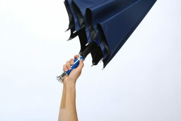 A person holding a 27in Black UV Single Layer Auto Golf Umbrella with a blue handle.