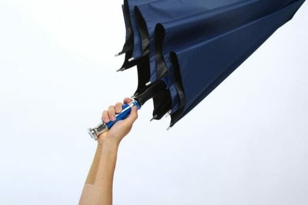 A person holding a 27in Black UV Single Layer Auto Golf Umbrella with a blue handle.