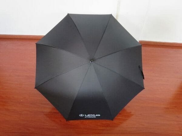 A 30inch Manual Open Golf Umbrella sitting on a wooden floor.