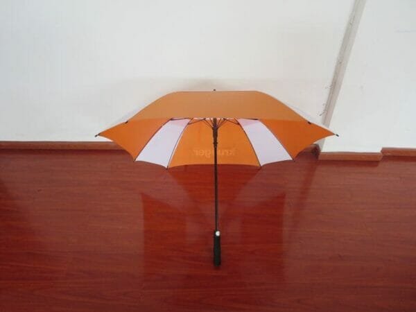 A 27inch Double Layer Golf Umbrella sitting on a wooden floor.