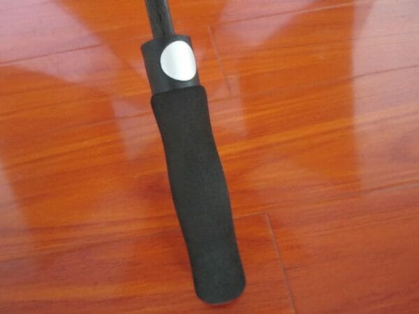 A 27inch Double Layer Golf Umbrella sitting on a wooden floor.