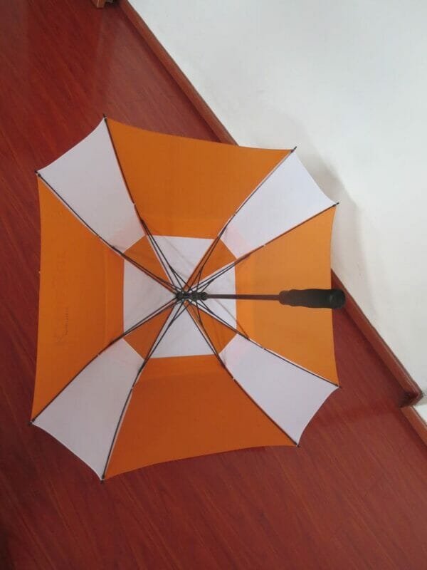 A 27inch Double Layer Golf Umbrella sitting on a wooden floor.