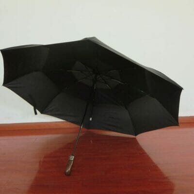 A 27inch Fold Golf Umbrella sitting on a wooden floor.