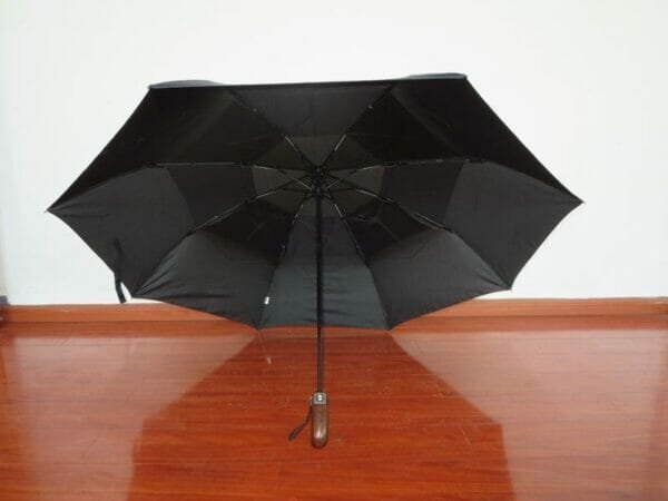 A 27inch Fold Golf Umbrella sitting on a wooden floor.