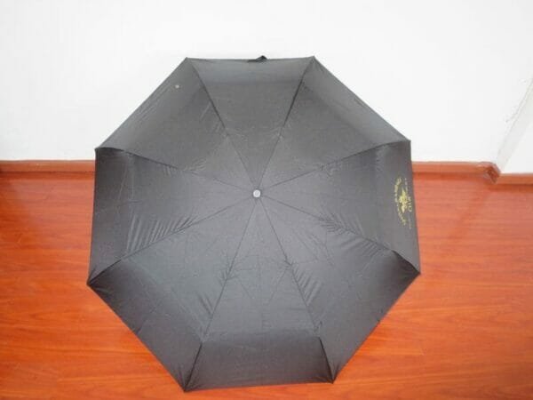 A 27inch Fold Golf Umbrella sitting on a wooden floor.