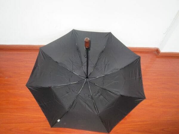 A 27inch Fold Golf Umbrella sitting on a wooden floor.