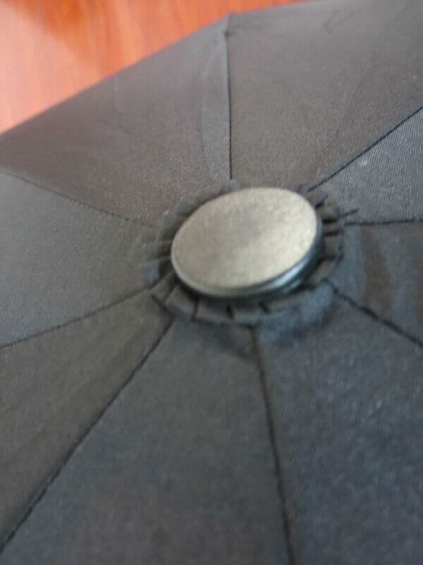 A close up of a 27inch Fold Golf Umbrella with a button on it.