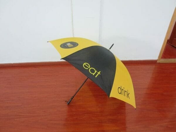 A yellow and black 30inch Cheap Golf Umbrella sitting on a wooden floor.