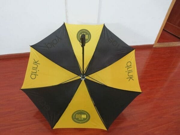 A yellow and black 30inch Cheap Golf umbrella on a wooden floor.