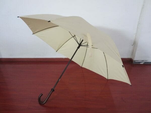 A 30 inch Manual Open Golf Umbrella Wood Handle sitting on a wooden floor.