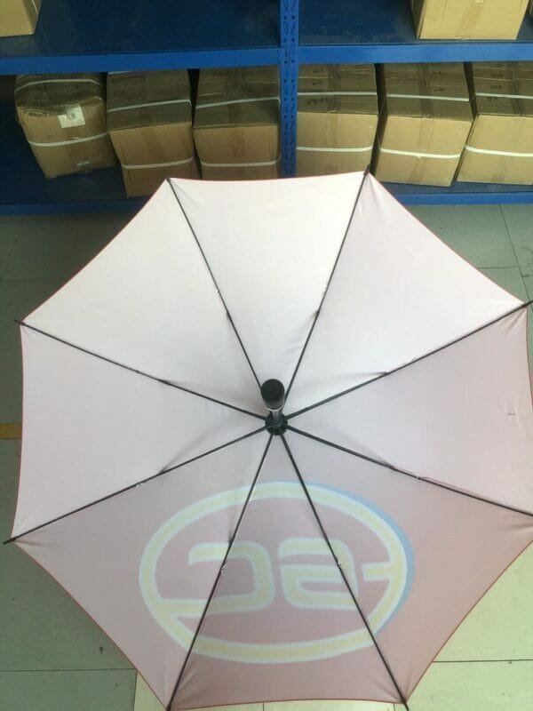 A 30in 280T Single Layer Auto Golf Umbrella is sitting on a table in a warehouse.