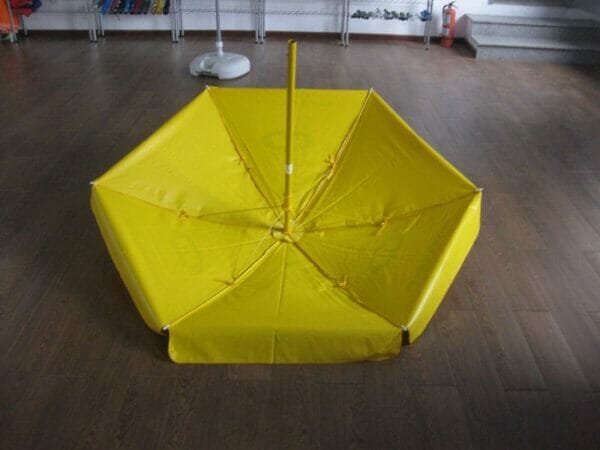 A 1.6m PVC Beach Umbrella sitting on a wooden floor.