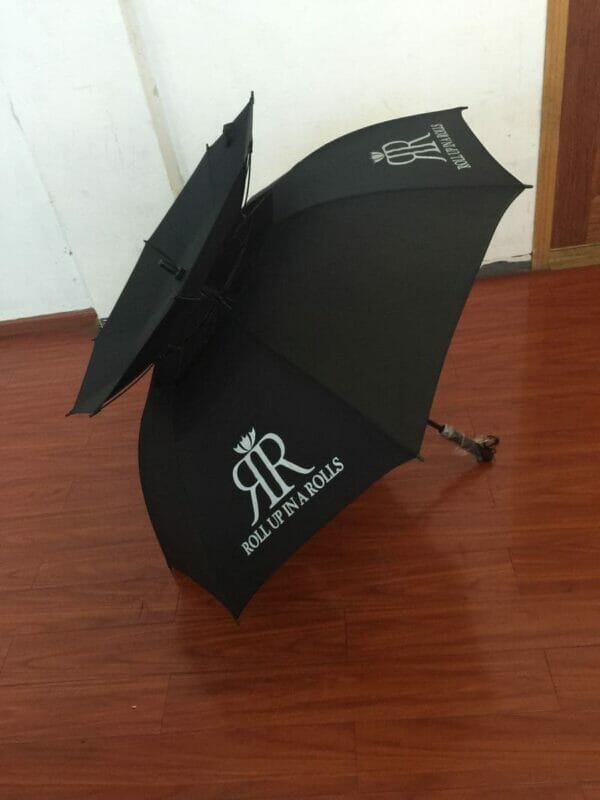 A black Double Layer Golf Umbrella Rubber Handle | ARDECO laying on a wooden floor.