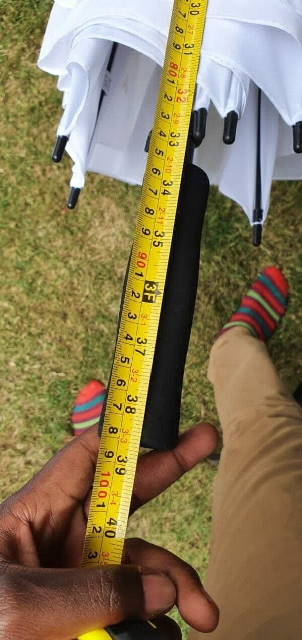 A person holding a measuring tape while holding a 23in/30in Single Layer Auto Golf Umbrella.