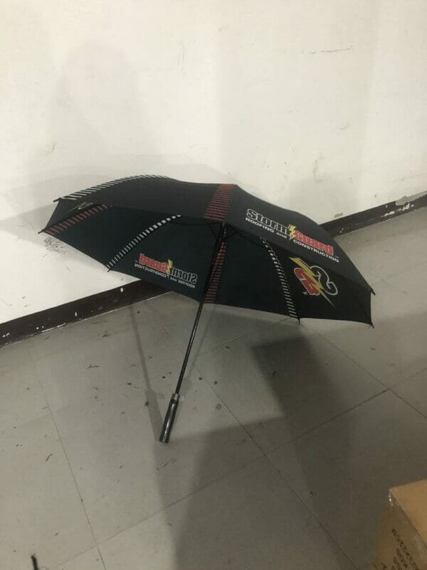 A 32in Single Layer Auto Golf Umbrella sitting on the floor of a room.