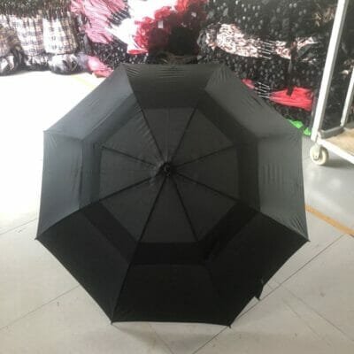 A 27inch Double Layer Golf Umbrella 190T sitting on a table in a warehouse.