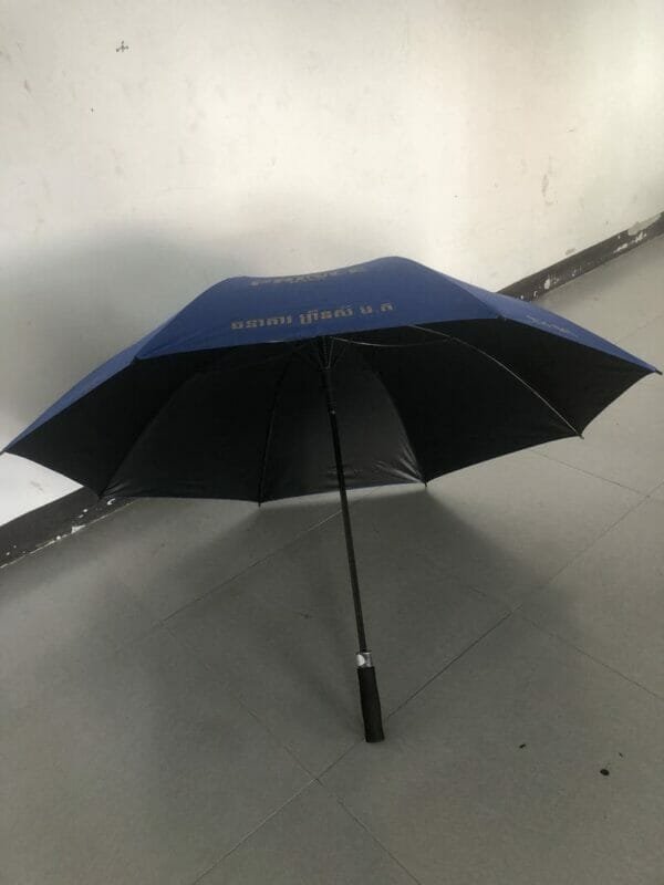 A 30in Black Single Layer Auto Golf Umbrella with a black handle sitting on a floor.