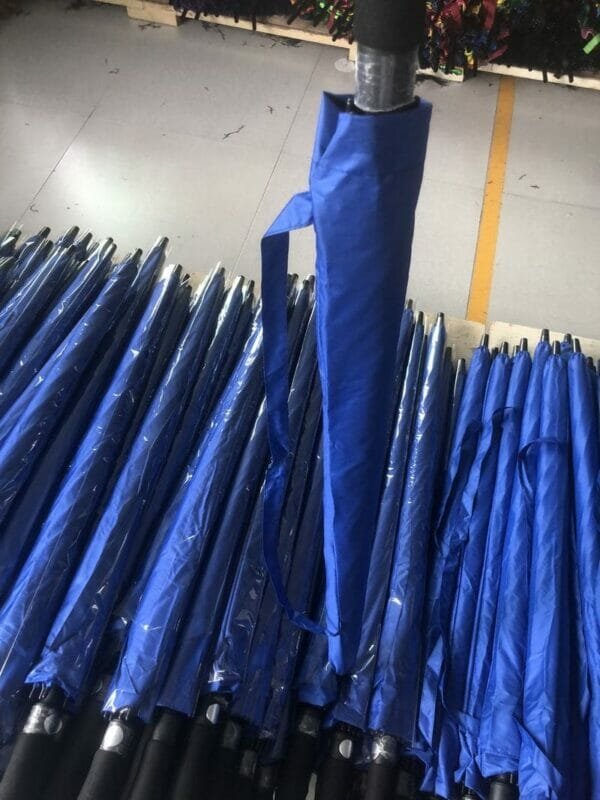 A group of 30in Black Single Layer Auto Golf Umbrellas in a warehouse.