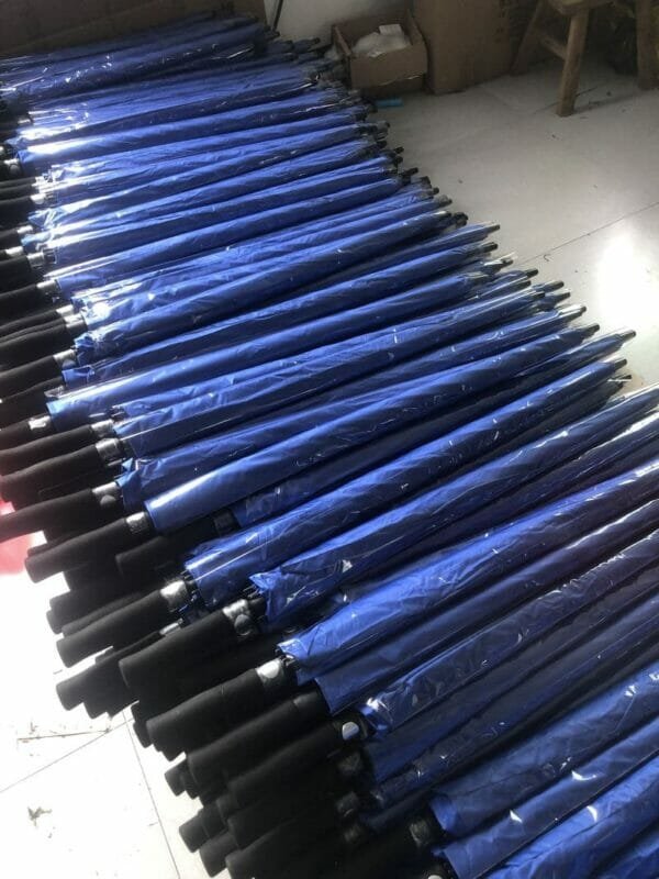 A group of 30in Black Single Layer Auto Golf Umbrellas stacked on top of each other.