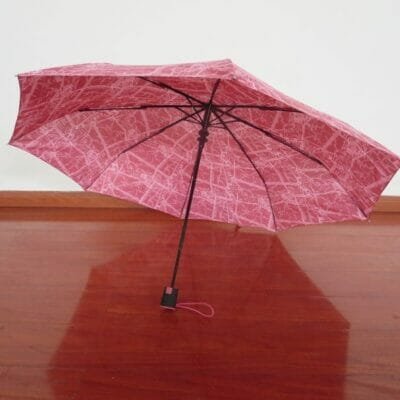 a wooden table holding a pink umbrella