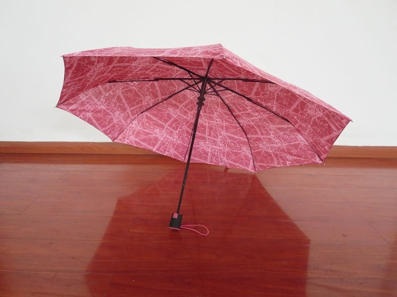 a wooden table holding a pink umbrella