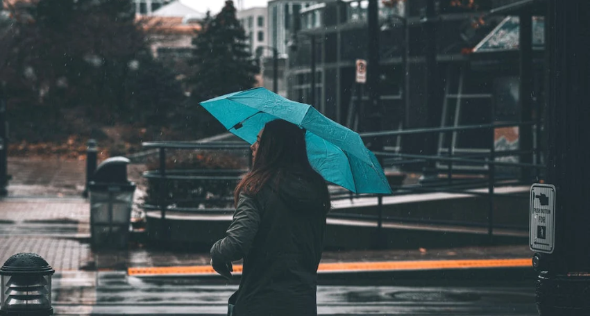 a person walking in the rain holding an inverted umbrella